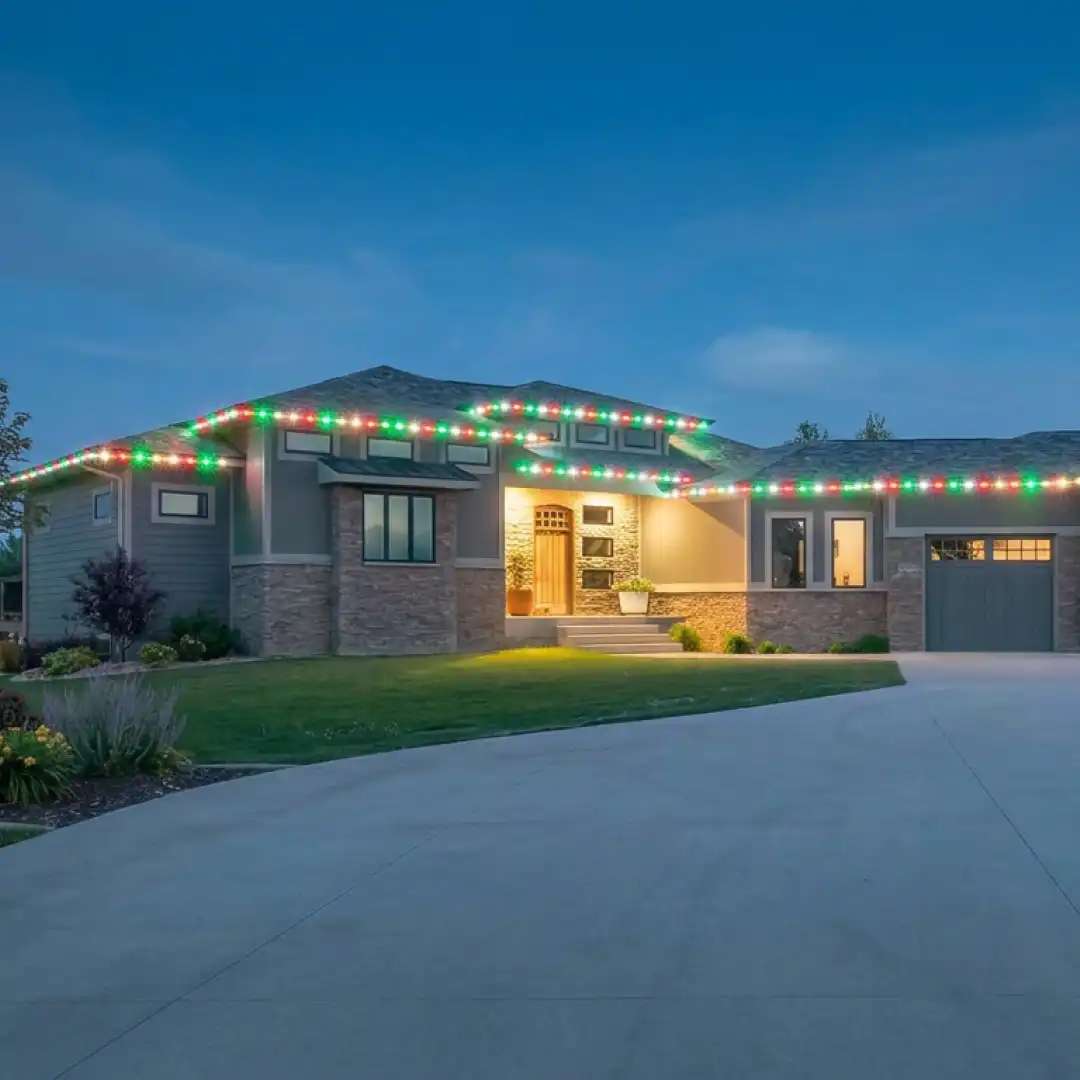 Permanent Christmas lights in classic red and green along the roofline of a suburban estate